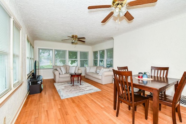 sunroom / solarium with plenty of natural light, a textured ceiling, wood finished floors, a deck, and baseboards
