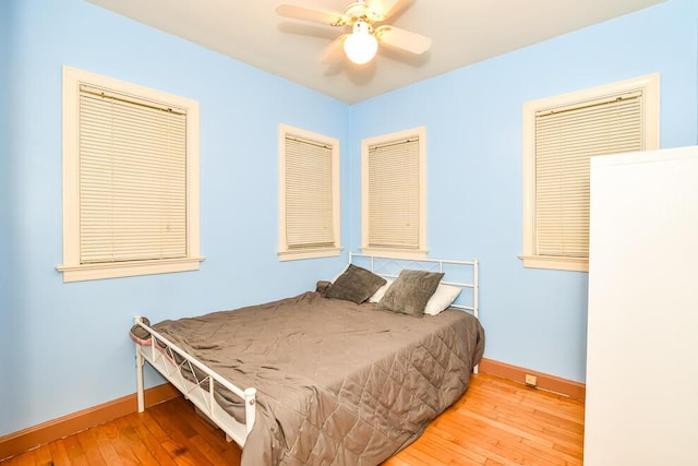bedroom with baseboards, hardwood / wood-style floors, and a ceiling fan