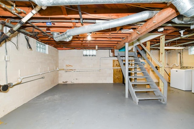 basement with stairs, concrete block wall, and separate washer and dryer
