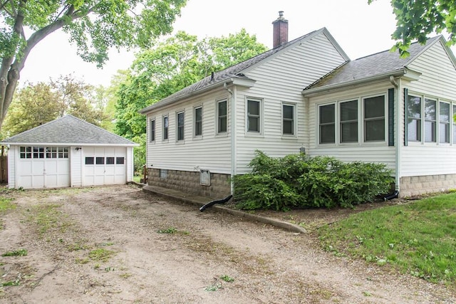 view of side of home with a chimney, an outdoor structure, a detached garage, and a shingled roof