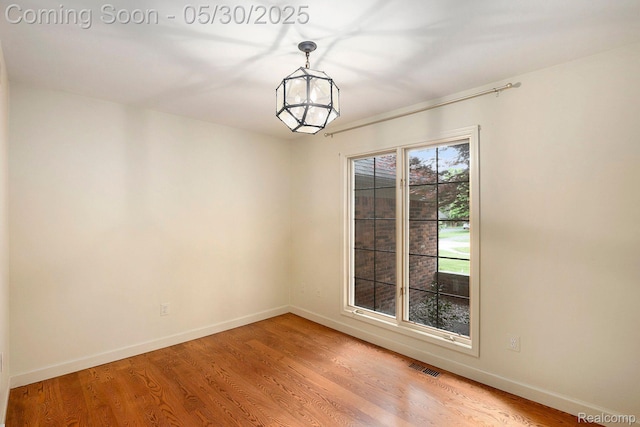 7254 Dark Lake Dr, Clarkston, MI 48346 - unfurnished room featuring baseboards, light wood-style floors, and a chandelier