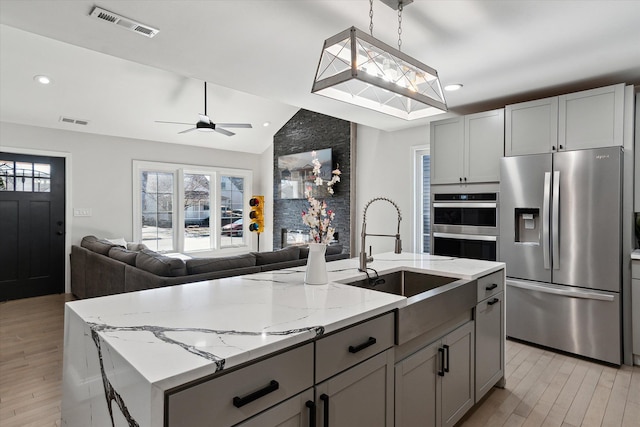 1826 Morris Ave, Lincoln Park, MI 48146 - kitchen featuring stainless steel appliances, open floor plan, a sink, vaulted ceiling, and light wood finished floors