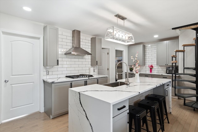 1826 Morris Ave, Lincoln Park, MI 48146 - kitchen featuring wall chimney exhaust hood, gray cabinets, light wood-style flooring, a sink, and stainless steel gas stovetop