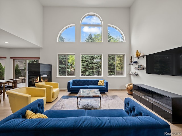 1231 Burns Dr, Troy, MI 48083 - living room with plenty of natural light, a glass covered fireplace, a towering ceiling, and wood finished floors