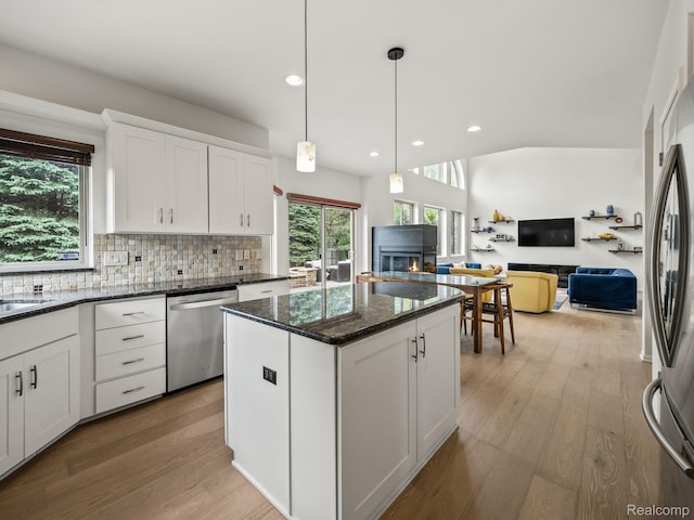 1231 Burns Dr, Troy, MI 48083 - kitchen featuring stainless steel appliances, a warm lit fireplace, light wood finished floors, tasteful backsplash, and recessed lighting