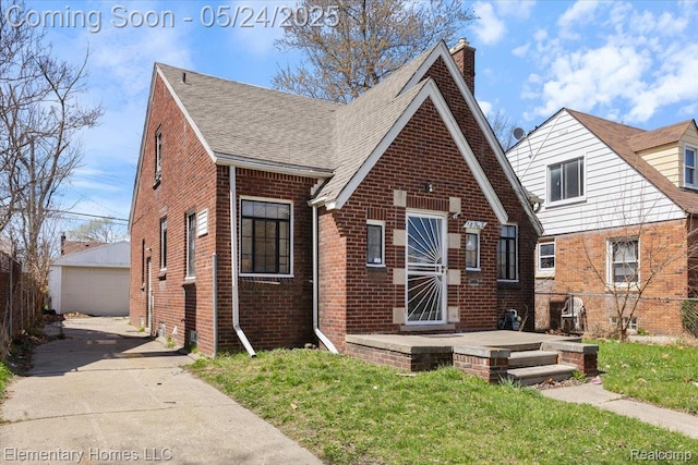 18965 Rutherford St, Detroit, MI 48235 - tudor house with brick siding, a detached garage, a chimney, a shingled roof, and an outbuilding