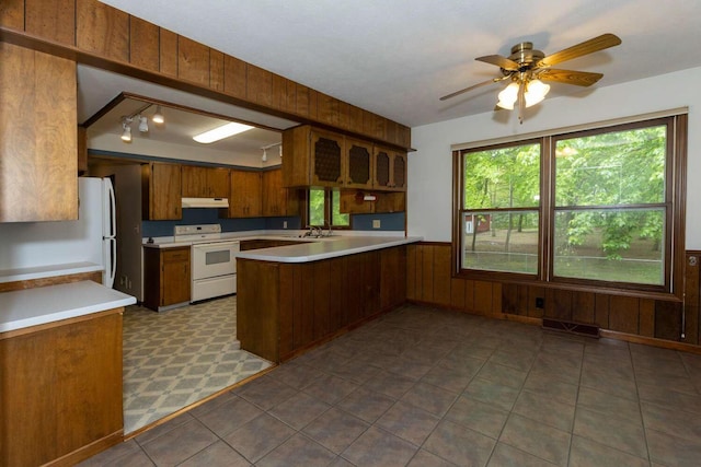 2967 152nd Ave, Holland, MI 49424 - kitchen with white appliances, a peninsula, under cabinet range hood, light countertops, and brown cabinets