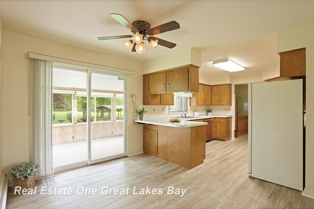 5354 N River Rd, Freeland, MI 48623 - kitchen with freestanding refrigerator, a peninsula, brown cabinetry, light countertops, and ceiling fan