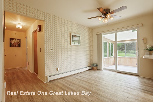5354 N River Rd, Freeland, MI 48623 - empty room with a baseboard radiator, wallpapered walls, baseboards, wood finished floors, and a ceiling fan