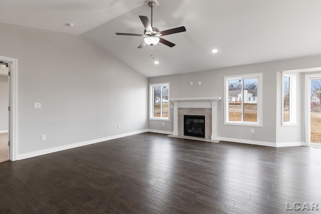 796 War Bonnet Dr, Tecumseh, MI 49286 - unfurnished living room featuring healthy amount of natural light, vaulted ceiling, a ceiling fan, a tiled fireplace, and dark wood finished floors