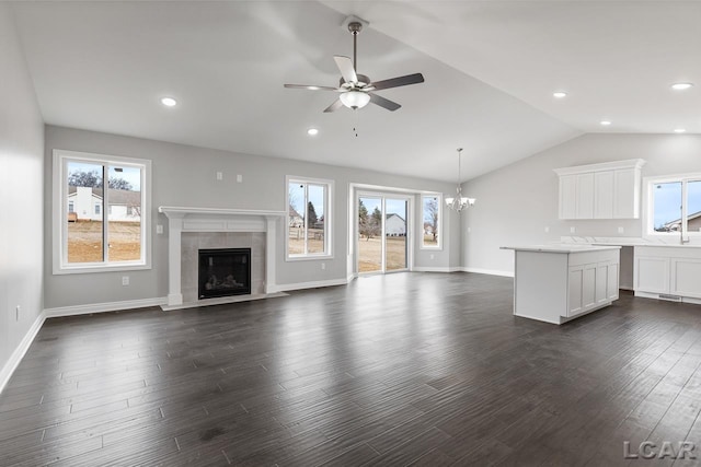 796 War Bonnet Dr, Tecumseh, MI 49286 - unfurnished living room with a tile fireplace, ceiling fan, a chandelier, vaulted ceiling, and dark wood-style floors