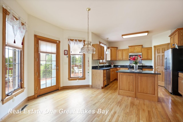 4168 Windemere Dr, Saginaw, MI 48603 - kitchen featuring stainless steel appliances, light wood-type flooring, a sink, dark countertops, and a center island