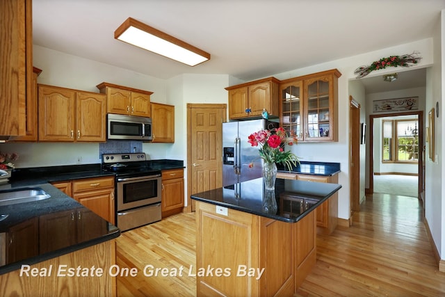 4168 Windemere Dr, Saginaw, MI 48603 - kitchen featuring appliances with stainless steel finishes, light wood finished floors, glass insert cabinets, and a kitchen island