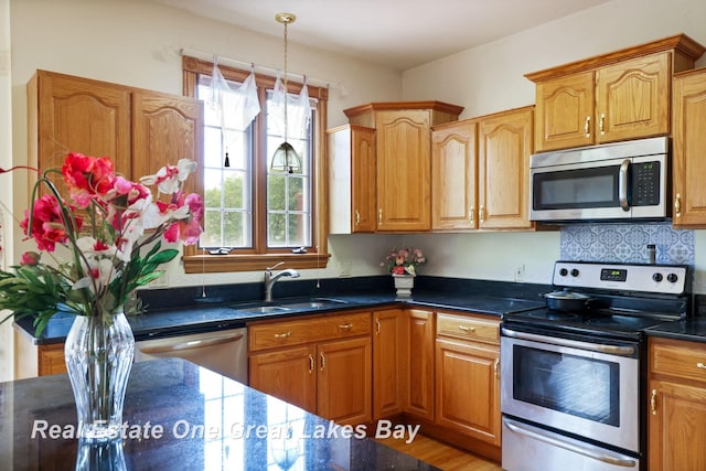 4168 Windemere Dr, Saginaw, MI 48603 - kitchen featuring stainless steel appliances, a sink, decorative light fixtures, and brown cabinetry