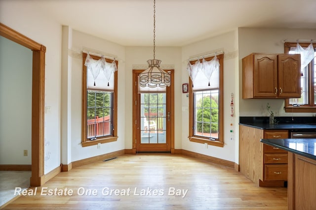 4168 Windemere Dr, Saginaw, MI 48603 - unfurnished dining area with light wood-style flooring, a chandelier, and baseboards