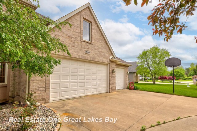 4168 Windemere Dr, Saginaw, MI 48603 - view of side of property featuring brick siding, a garage, concrete driveway, and a yard