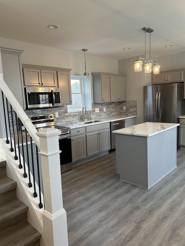 kitchen featuring appliances with stainless steel finishes, gray cabinetry, a sink, decorative backsplash, and light countertops
