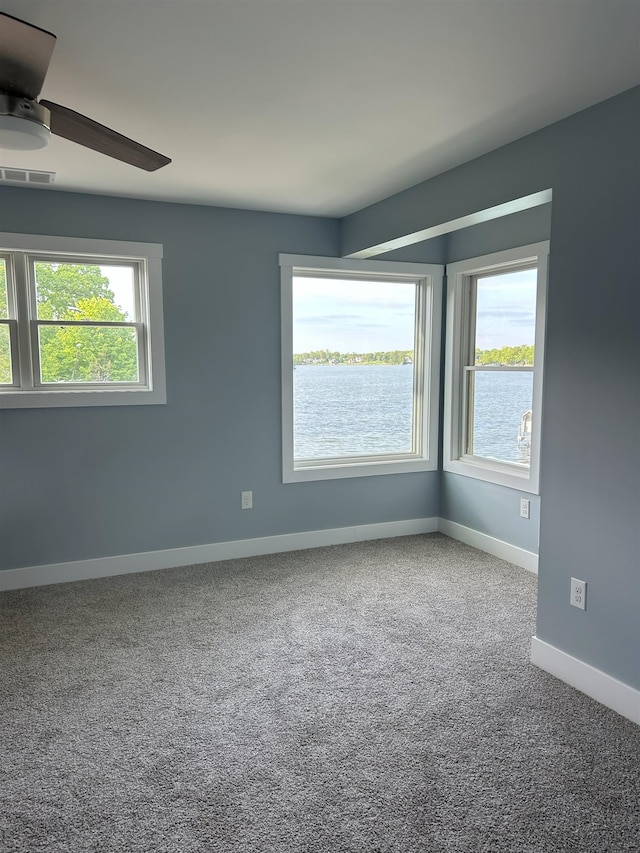 empty room featuring ceiling fan, healthy amount of natural light, carpet floors, and baseboards