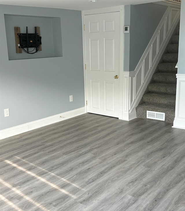 unfurnished living room with wood finished floors, stairs, and baseboards