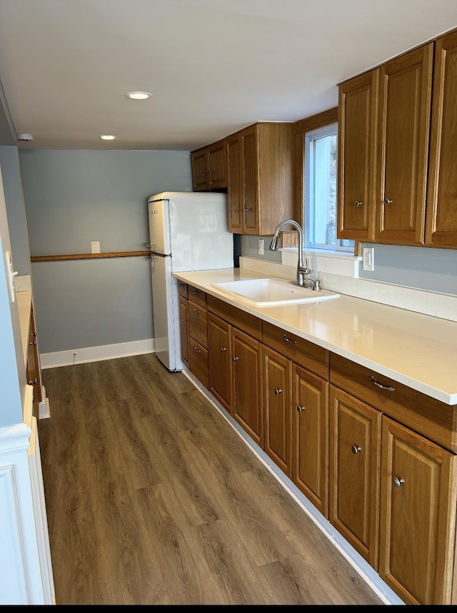 kitchen with a sink, dark wood finished floors, light countertops, brown cabinets, and recessed lighting