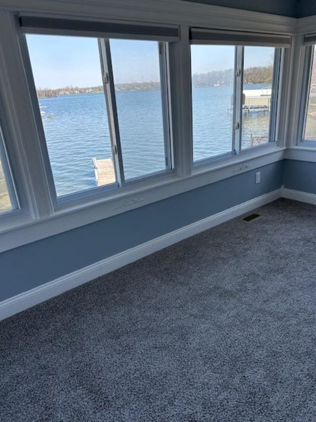 empty room with a water view, dark colored carpet, and baseboards