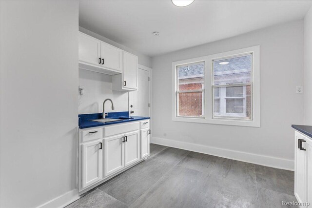 12242 Washburn St, Detroit, MI 48204 - kitchen with a sink, baseboards, dark countertops, and white cabinets