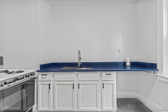 12242 Washburn St, Detroit, MI 48204 - kitchen featuring a sink, gas range oven, dark countertops, and white cabinetry