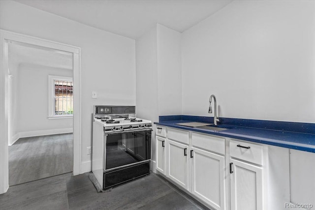 12242 Washburn St, Detroit, MI 48204 - kitchen with gas range, dark wood-type flooring, a sink, white cabinetry, and dark countertops