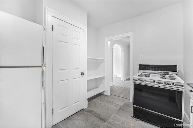 12242 Washburn St, Detroit, MI 48204 - kitchen with range with gas stovetop, freestanding refrigerator, and arched walkways
