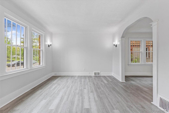 12242 Washburn St, Detroit, MI 48204 - unfurnished room with wood finished floors, a textured ceiling, arched walkways, and baseboards