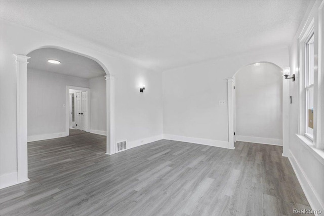 12242 Washburn St, Detroit, MI 48204 - spare room featuring arched walkways, wood finished floors, a textured ceiling, and baseboards