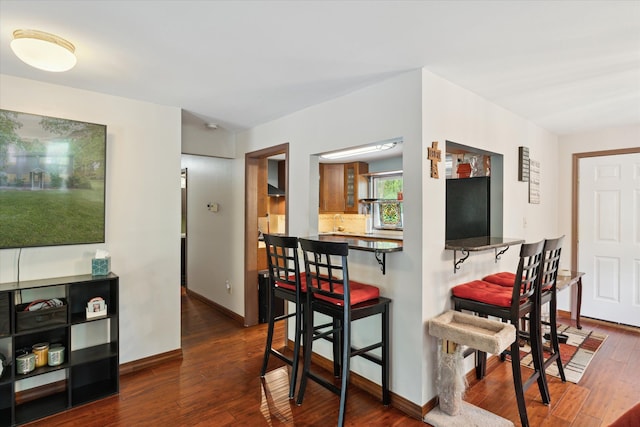 6544 Woodland Rd, Whitmore Lake, MI 48189 - kitchen with dark wood finished floors, a kitchen bar, dark countertops, and baseboards