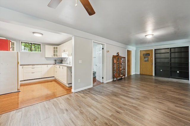 6544 Woodland Rd, Whitmore Lake, MI 48189 - unfurnished living room with a ceiling fan, light wood-type flooring, a sink, and baseboards