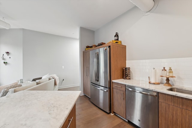 804 N Main St Unit 2C, Rochester, MI 48307 - kitchen featuring stainless steel appliances, wood finished floors, tasteful backsplash, light stone countertops, and brown cabinets