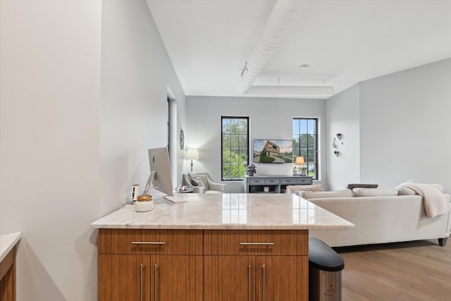804 N Main St Unit 2C, Rochester, MI 48307 - kitchen featuring open floor plan, a peninsula, brown cabinetry, light wood-type flooring, and light stone counters