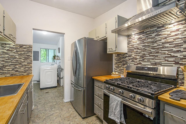2753 Cumberland Ave, Ann Arbor, MI 48104 - kitchen with wooden counters, stainless steel appliances, washing machine and dryer, wall chimney exhaust hood, and tasteful backsplash