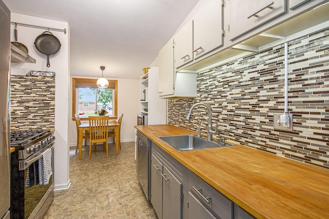 2753 Cumberland Ave, Ann Arbor, MI 48104 - kitchen with appliances with stainless steel finishes, a sink, butcher block countertops, backsplash, and baseboards