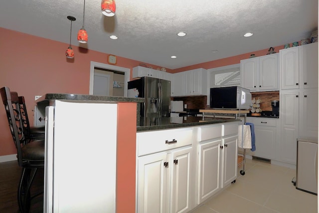 113 Davis Dr, Brooklyn, MI 49230 - kitchen with black fridge with ice dispenser, a textured ceiling, white cabinetry, decorative backsplash, and a kitchen island