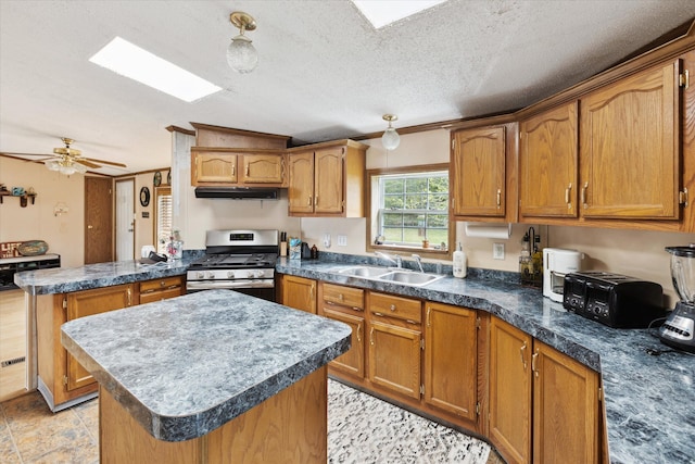 9168 Clewley Rd, Lachine, MI 49753 - kitchen with stainless steel range with gas cooktop, a peninsula, a sink, a kitchen island, and brown cabinetry
