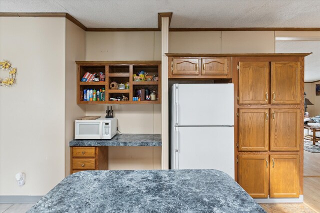 9168 Clewley Rd, Lachine, MI 49753 - kitchen with white appliances, crown molding, brown cabinets, and a textured ceiling