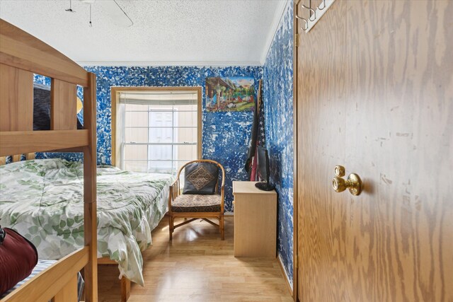 9168 Clewley Rd, Lachine, MI 49753 - bedroom featuring wallpapered walls, a textured ceiling, wood finished floors, and ornamental molding