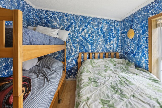 9168 Clewley Rd, Lachine, MI 49753 - bedroom with wallpapered walls, crown molding, and wood finished floors