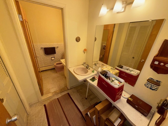 1233 Island Dr Unit 203, Ann Arbor, MI 48105 - bathroom with baseboard heating, toilet, a sink, tile walls, and tile patterned flooring