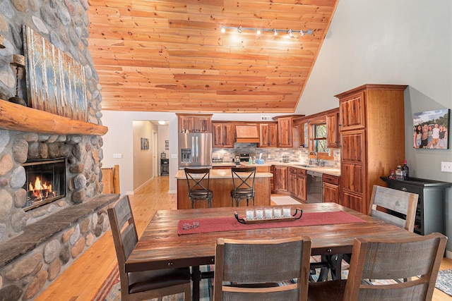 5301 Durga Rd, Williamsburg, MI 49690 - dining room featuring wood ceiling, high vaulted ceiling, light wood finished floors, track lighting, and a stone fireplace