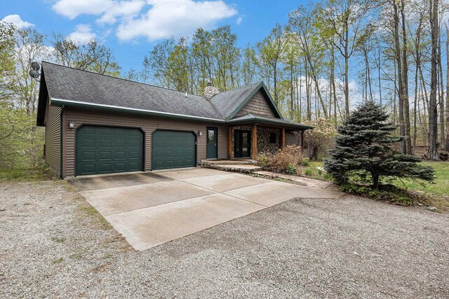 5301 Durga Rd, Williamsburg, MI 49690 - view of front of home with an attached garage, concrete driveway, a chimney, and covered porch