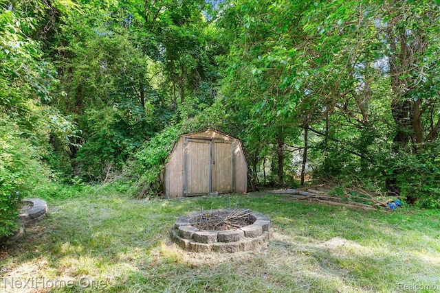 7469 Longworth Dr, Brighton, MI 48116 - view of yard with a storage shed, a fire pit, and a forest view
