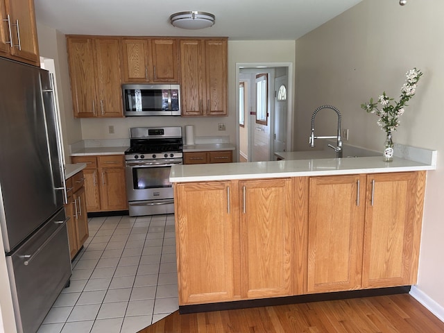 4139 Yorba Linda Blvd, Royal Oak, MI 48073 - kitchen featuring appliances with stainless steel finishes, a peninsula, light countertops, and brown cabinetry