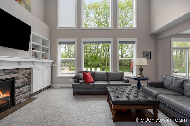 9012 N Wolven Ridge Ct, Rockford, MI 49341 - living room featuring a high ceiling, a stone fireplace, and baseboards