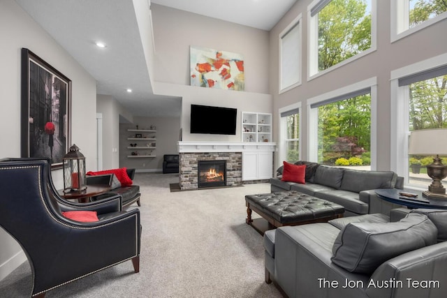 9012 N Wolven Ridge Ct, Rockford, MI 49341 - carpeted living room featuring a high ceiling, a stone fireplace, built in features, recessed lighting, and baseboards