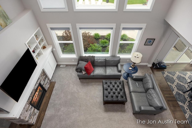 9012 N Wolven Ridge Ct, Rockford, MI 49341 - carpeted living room featuring a towering ceiling, a stone fireplace, and baseboards